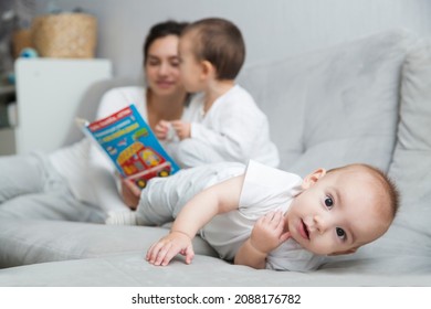 Mom Plays And Reads Books With Two  Little Kids. Mother Spends Time With Two Child Sons At Home.  Place For Text. Copy Space. Family Time At Home
