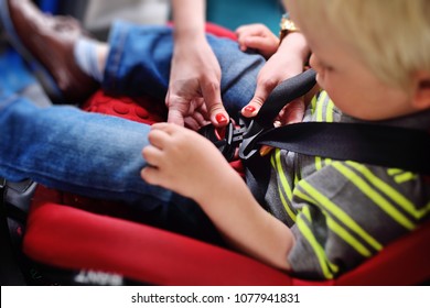 Mom Puts The Child In The Car Seat And Fasten Seat Belts. Safe Transportation Of Children In The Car