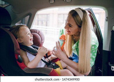 Mom Puts Her Little Son In A Car Seat And Buckles Him