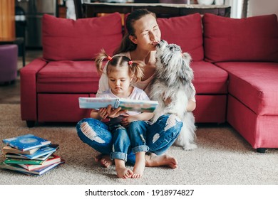 Mom Reading Book With Baby Girl Toddler At Home. Funny Home Lifestyle Family With Licking Pet Dog. Early Age Children Education Development. Family Authentic Candid Lifestyle. 