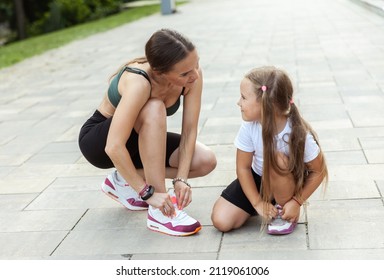 Mom runner and her little daughter tie their shoelaces before jogging outdoors. Active family concept - Powered by Shutterstock