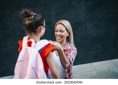 Mom Saying Goodbye To Her Daughter Before Going To School. Back To School And Education Concept. 