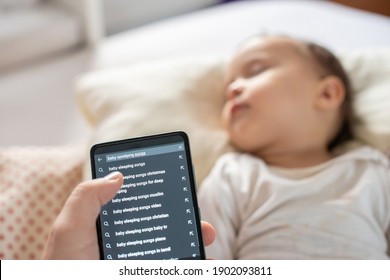 Mom searching the internet using her phone for baby sleeping songs