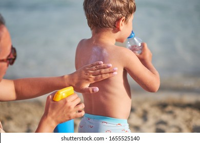 Mom Smears Her Baby Skin Sun Cream On Beach. Sunscreen.