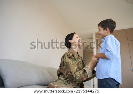 Mom soldier and son communicate cutely in a bright room