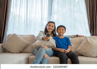 Mom And Son Asian Couple Watching TV On A Sofa At Home With Enjoy Happy