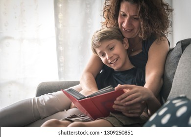Mom son have fun looking old photographs pictures sitting sofa home album memories blond child with curly woman smile happy leafing through photos. Family domestic scene White modern furniture - Shutterstock ID 1309250851