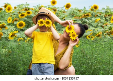 Mom And Son Hug, Laugh And Play In A Field Of Sunflowers. Happy Family Moments Spent In The Open Air. Mother's Day.