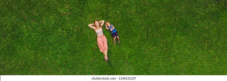 Mom and son are lying on the grass in the park, photos from the drone, quadracopter. BANNER long format - Powered by Shutterstock