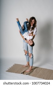 Mom and son photoshoot in the studio. Mom kisses her son. play together have fun laughing and rejoicing. to hang upside down. isolated. young parents. boy with mother