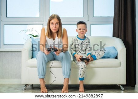 Mom and son play video games at home on the couch