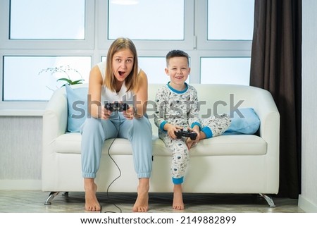 Mom and son play video games at home on the couch