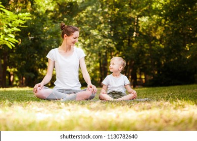 Mom and son are practicing yoga in the park. - Powered by Shutterstock