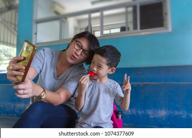 Mom And Son Selfie With Mobile Phone Background. Asian Black Hair 40s Woman And 4 Years Old Boy Happiness To Using Smart Phone Taking Photos Or Video Calling With Selective Focus And Copy Space