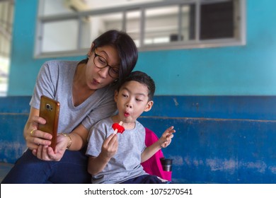 Mom And Son Selfie And Say Wow With Mobile Phone Background. Asian Black Hair 40s Beautiful Woman And Cute Boy Age 4 Years Old Happiness To Using A Smartphone Taking Photos Or Video For Social Media.