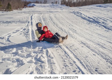 Mom And Son Sledding On The Mountain