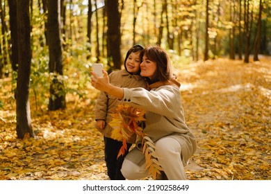 Mom And Son Take A Selfie On The Phone In The Autumn Forest. People Use Technology. Autumn Outdoor Activity For Family With Kids. Happy Mother's Day. Family Day. Autumn Day. Happy Family Leisure.