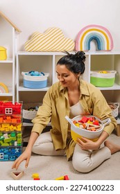 Mom sorted by colors and puts children's toys in transparent boxes and storage baskets. Mother tidy up the childrens room. Organization and Storage Ideas in playroom.  - Shutterstock ID 2274100223