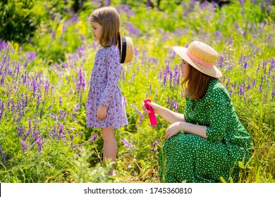 The Mom Spray Treatment The Daughter The Means From Mosquitoes And Ticks For A Walk In The Summer Field. Family Walks On The Nature.