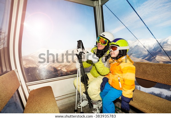 Mom talk to\
child sitting in ski lift cabin\
