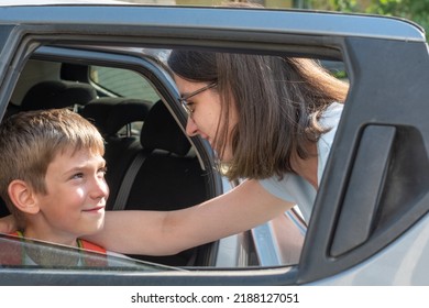 Mom Talks To Her Son Through The Car Window, Wishes Him Success At School. Happy Child Sitting In The Car Talking To Mom. The Concept Of Returning To School.