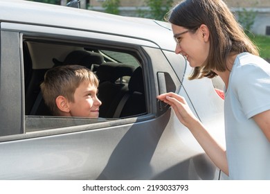 Mom Talks To Her Son Through The Car Window, Wishes Him Success At School. Happy Child Sitting In The Car Talking To Mom. The Concept Of Returning To School.