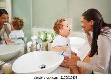 Mom Teaching Baby To Brush Its Teeth, On The Bathroom Counter In Home And A Clean Smile On Her Face. Healthy Oral Hygiene For Kid Means Using Child Friendly Toothpaste, Toothbrush And Dental Routine