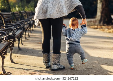 Mom Teaching Her Son's First Baby Steps In The Park