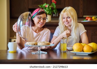 Mom And Teenage Daughter Eating Together, Sitting At Table At Home In Kitchen