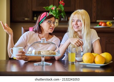 Mom And Teenage Daughter Eating Together, Sitting At Table At Home In Kitchen