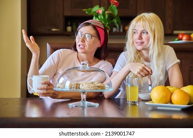 Mom And Teenage Daughter Eating Together, Sitting At Table At Home In Kitchen