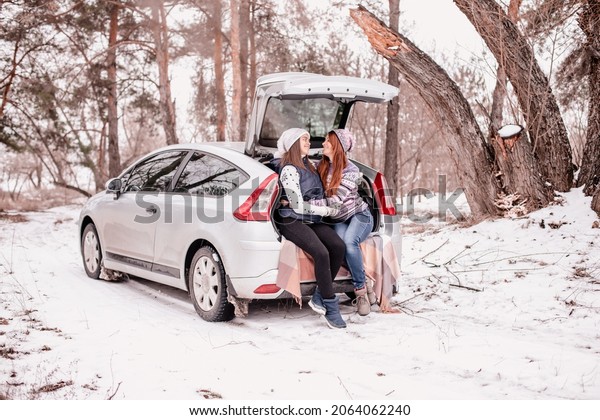 Mom and teenage daughter together.\
Two girls are sitting in the trunk of a car in winter.\
