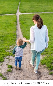 Mom With A Toddler Is On Treck. Mum With The Child Climbs Up The Hill. Little Boy With His Mother Walking Along The Road On The Hill In The Parkin The Summer.