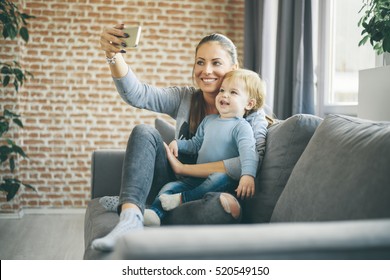 Mom And Toddler Taking Selfie In Cosy Living Room
