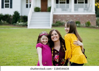 Mom And Two Daughters Being Silly Having Fun Laughing Outside Their Home