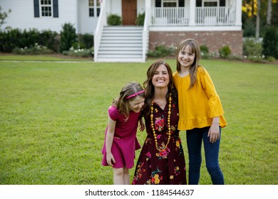 Mom And Two Daughters Being Silly Having Fun Laughing Outside Their Home