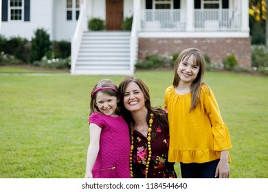 Mom And Two Daughters Being Silly Having Fun Laughing Outside Their Home