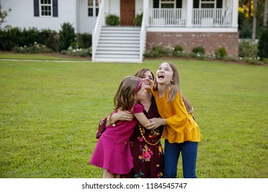 Mom And Two Daughters Being Silly And Laughing Outside Their New Farmhouse Home