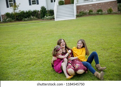 Mom And Two Daughters Being Silly And Laughing Outside Their New Farmhouse Home