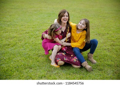 Mom And Two Daughters Being Silly And Laughing Outside Their New Farmhouse Home