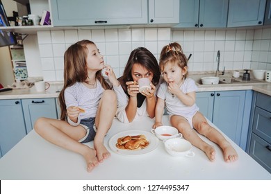 Mom And Two Daughters Eat Pancakes In The Kitchen