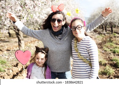 Mom and two daughters have fun in carnival costumes outdoors