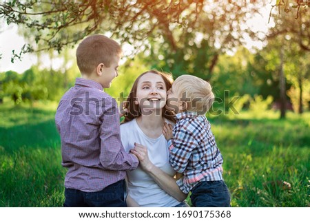 Mom with two sons in the Park. Child is kissing his mother. Happy motherhood.