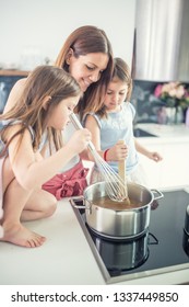 Mom With Two Young Twins Daughters In The Kitchen Cooking Spaghetti.