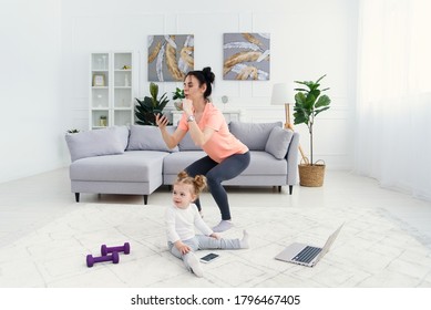 Mom Uses Smart Phone While Doing Morning Work-out At Home. Mother Does Fitness Exercises, Healthy Lifestyle Concept.