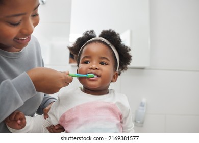 Mom Will Help Her Keep Her Baby Teeth Clean. Shot Of A Mother Brushing Her Little Daughters Teeth In The Bathroom At Home.