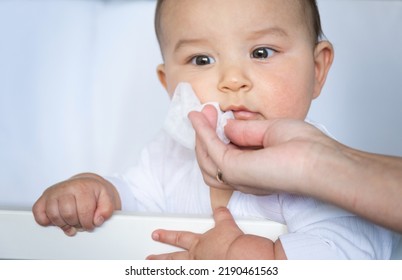 Mom Wipes The Baby's Drool With A Napkin. Baby Care, Teething, Drooling.