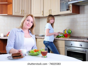 Mom And Young Daughter Eating Breakfast Together In The Kitchen