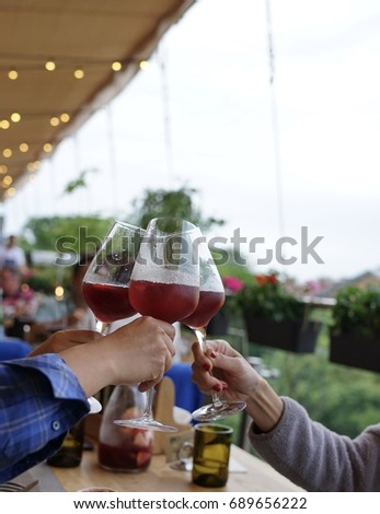 A moment of 3 people toasting 3 glasses of wine celebrating their special occasion on long term friendship in a restaurant with a beautiful garden view