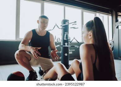 moment of active conversation between a knowledgeable personal trainer and a female client, as they exchange exercise tips and engage in a productive dialogue at the gym.